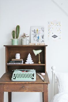 an old fashioned desk with a typewriter and cactus in the corner next to it