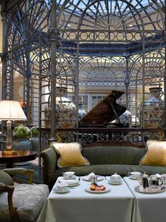 a living room filled with furniture and a grand piano in the center surrounded by glass walls