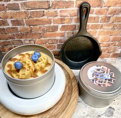 a bowl of food sitting on top of a wooden plate next to a pot and pan