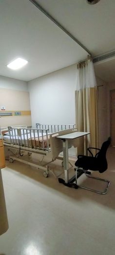 an empty hospital room with two beds and a desk