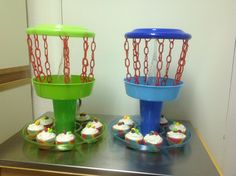 two cupcakes in plastic cups with chains attached to them on top of a table