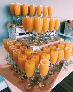 a table topped with lots of glasses filled with orange juice