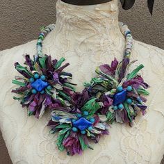 a necklace made out of paper flowers and beads on a mannequin neckline