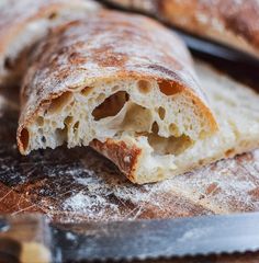 a close up of bread on a cutting board with a knife in the foreground