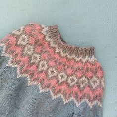 an old sweater is laying on top of a blue surface with pink and gray designs