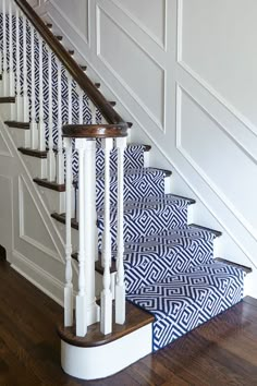 blue and white carpeted stairs with wooden handrails in an otherwise empty house