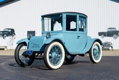 an old blue car parked in front of a building