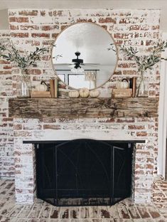 a fireplace with a mirror above it and some pumpkins sitting on the mantel