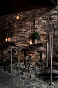 an image of a restaurant setting with tables and stools on the floor, in front of a brick wall