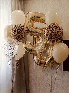 some balloons that are in the shape of number five and leopard print on one balloon