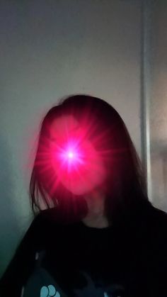 a woman with her head turned to the side, wearing a red light in front of her face