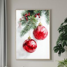 two red ornaments hanging from a christmas tree branch on a white wall next to a potted plant