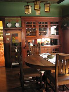 a dining room table and chairs in front of a hutch with plates on it