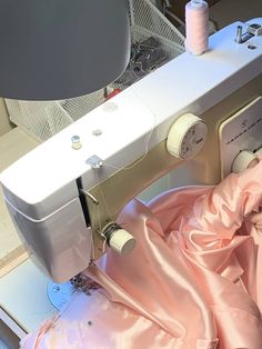 the sewing machine is next to some pink material