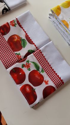 two napkins with apples printed on them sitting on a table next to each other