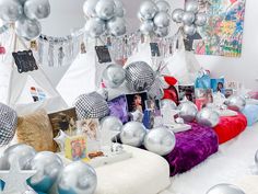 a room filled with lots of silver balloons and pictures hanging from the ceiling above it