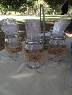 four mason jars are sitting on a table with twine and burlocks tied around them