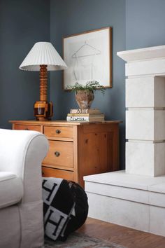 a living room with blue walls and white furniture, including a lamp on top of a dresser