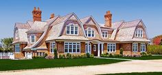 a large brown and white house sitting on top of a lush green field