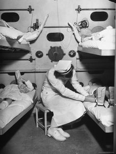 an old black and white photo of some people in a room with bunkbeds