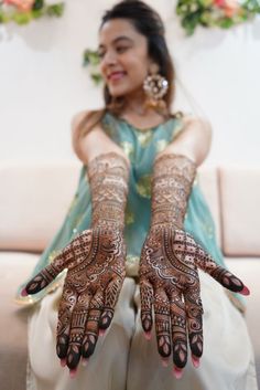 a woman sitting on top of a couch covered in hendix and holding her hands up