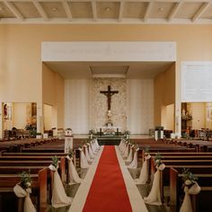 the interior of a church with pews and red carpet on the floor, decorated with greenery