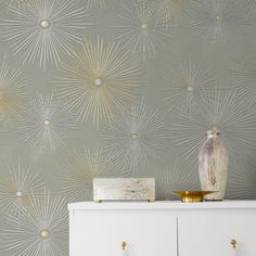 a white dresser sitting next to a green wallpaper with gold stars on the side