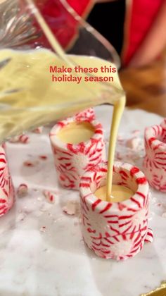 someone is pouring orange juice into small candy cups on a plate with red and white candies