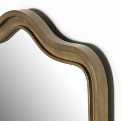 a mirror that is on the wall with some kind of curved frame around it's edge