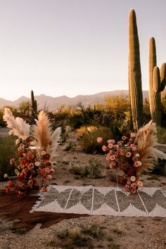 two vases filled with flowers sitting on top of a table next to cactus plants