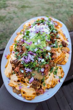 a white plate topped with pasta and meat covered in cheese, onions and cilantro