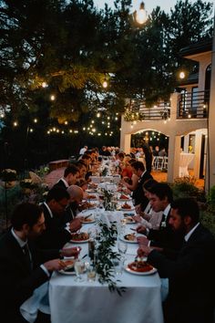 a group of people sitting at a long table with plates of food in front of them