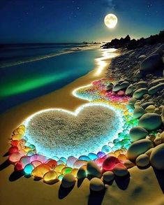 a heart made out of rocks on the beach at night with moon and stars in the sky