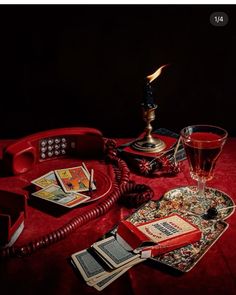 a red phone sitting on top of a table next to a glass filled with liquid