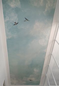 two birds are flying in the sky on a painted ceiling above an open door leading to another room