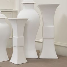 three white vases sitting next to each other on the floor