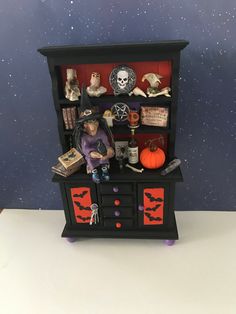 a doll house with halloween decorations on the top shelf and shelves above it, in front of a space filled with stars