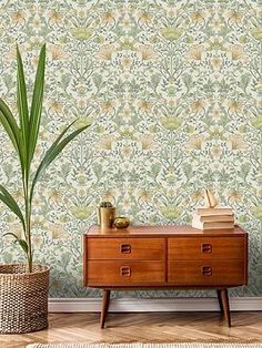 a living room with a chair, plant and wallpaper on the walls next to a dresser