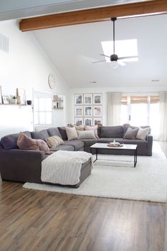 a living room filled with furniture on top of a hard wood floor covered in white rugs