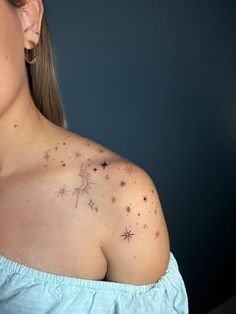 a woman's back with stars on her left shoulder and small tattoos on her right arm