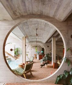 a circular mirror reflecting the inside of a room with chairs and potted plants in it