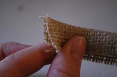 a hand holding a piece of burlock in it's left side, with the tip of its needle pointed out