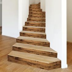 there is a set of wooden stairs in the house with white walls and wood flooring