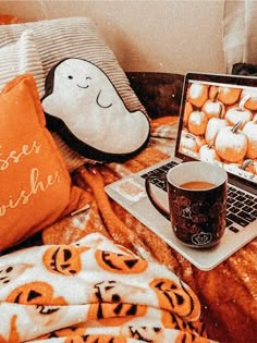 a laptop computer sitting on top of a bed next to a cup of coffee and a pillow