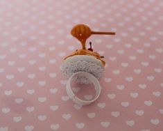 a ring with a piece of cake on it sitting on a pink table cloth covered in hearts