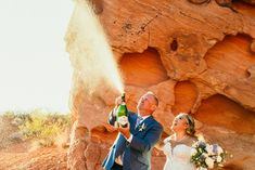 a bride and groom standing in front of a rock formation