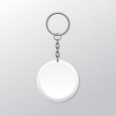 a white round keychain hanging from a metal ring on a gray background with clippings