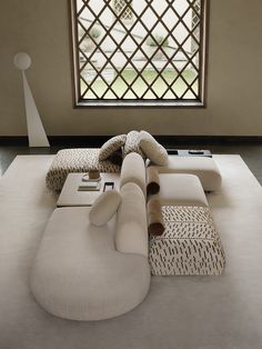 a large white couch sitting on top of a floor in front of a big window