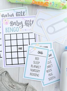 baby shower games and diapers laid out on a white wooden table next to a bottle of milk