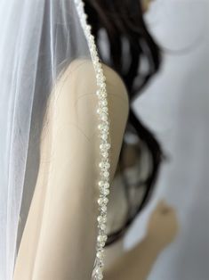 a woman wearing a wedding veil with pearls on it